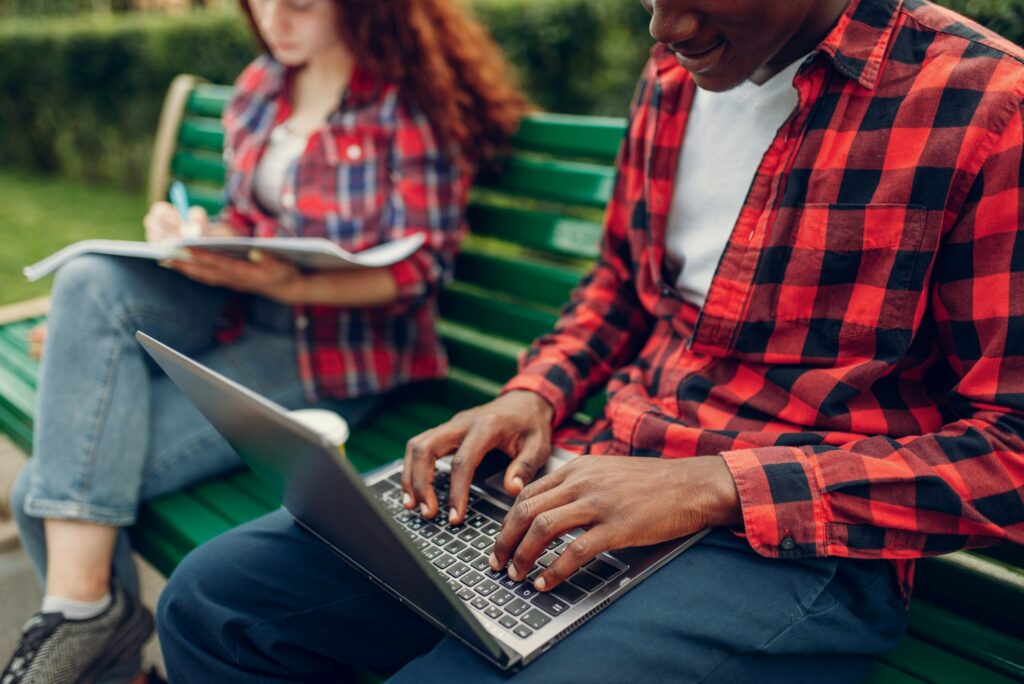 Two students studying on the bench in summer park